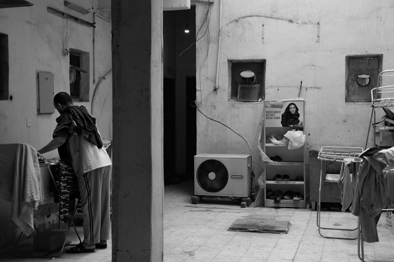 Photograph of a migrant working-class man doing his laundry in a shared accommodation in downtown Kuwait. Photography by Shather Naqi for Noema Magazine.
